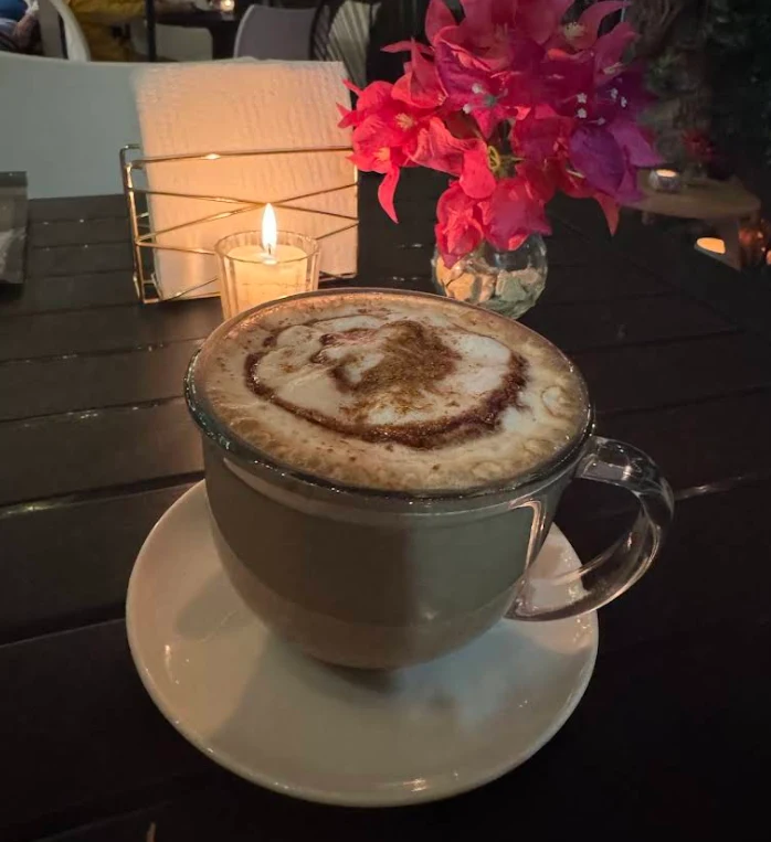 Una taza de café en una mesa de Aleida junto a flores